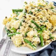 Salmon and potato salad on white plate with serving utensils.