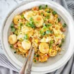 Fried rice with scallops in grey bowl with fork and spoon.