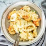 Risotto with seafood in grey bowl with fork and spoon.