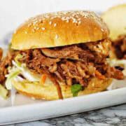 Pulled pork burger with coleslaw on a white plate.