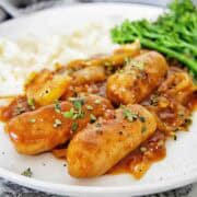 Devilled sausages on a white plate garnished with parsley.