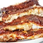 Cooked ribs with bbq sauce on white plate.