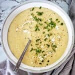Potato and leek soup in grey bowl with spoon.