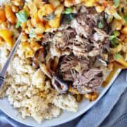 Cooked lamb on large plate with cous cous and apricot relish.