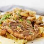 Cooked pork chops with mashed potatoes on white plate.