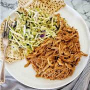 Pulled pork tenderloin on white plate with pita bread and salad.