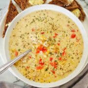 Slow cooker sausage potato soup in white bowl garnished with thyme leaves.