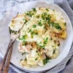 Scalloped potatoes and ham on white plate with chopped parsley.