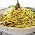 Fork being twirled in grey bowl of spaghetti al pesto.