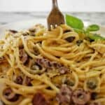 Fork being twirled in spaghetti gorgonzola on white plate