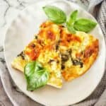 Two slices of spinach and feta pizza on a white plate.