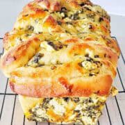 Cooked loaf of spinach and feta bread cooling on rack.
