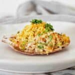 Stuffed scallop with chopped parsley on white plate.