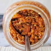 Sundried Tomato Pesto in a jar on its side with a spoon coming out
