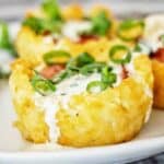 Loaded tater tot cup on white plate with drizzle of sauce.