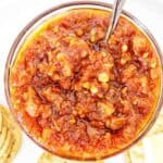 Bacon and tomato jam in a small glass bowl with silver spoon.