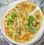 Tortilla garlic bread cut into sliced on white plate with basil leaves.