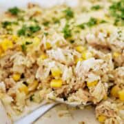 Spoon holding tuna and rice with corn in casserole dish.