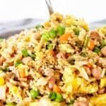 Spoon in large plate of fried rice.