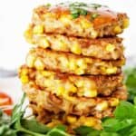 Tuna fritters stacked on white plate with parsley.
