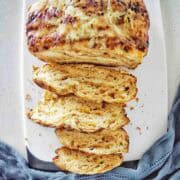 Loaf of vegemite bread sliced into pieces on a white cutting board.