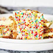 White chocolate crack broken into pieces on white plate.