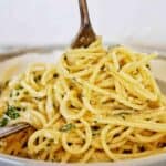 Fork being twirled in grey bowl of spaghetti.